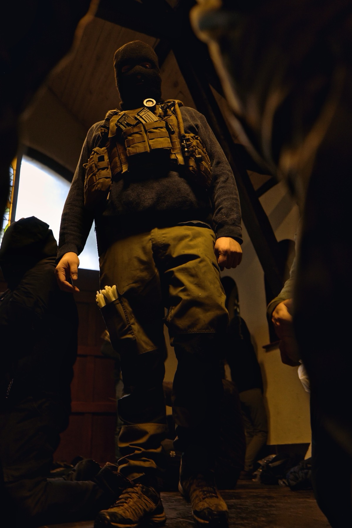 Masked captor standing over hostages